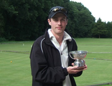 Young guy with peaked cap holding a silver trophy