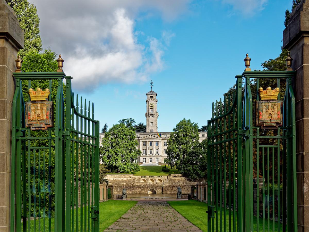 a pair of huge impressive wrought iron gates open with a vista to the grand Trent building