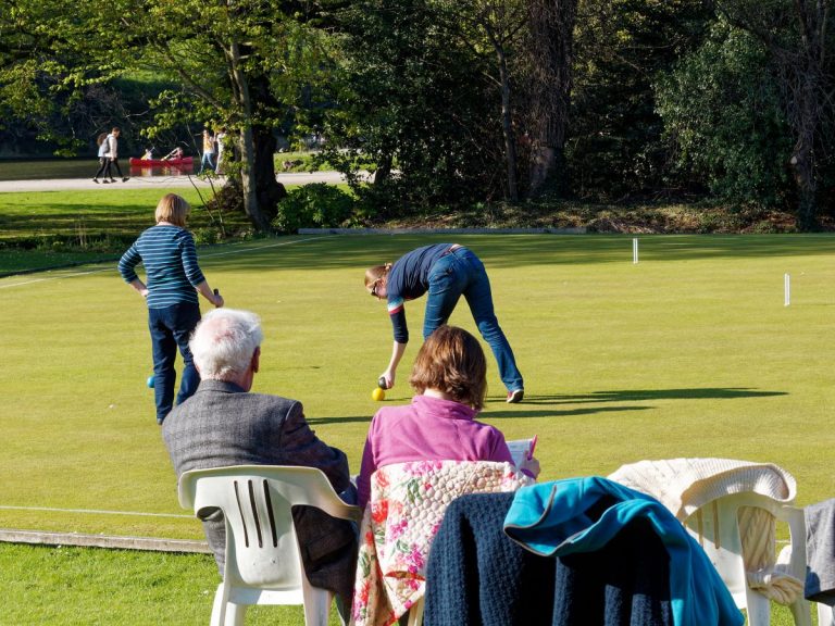 players and spectators in casual dress enjoying social croquet on a sunny afternoon