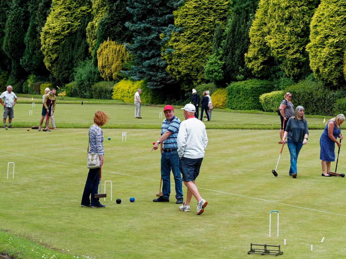 Visitors in action - playing on lawns 6-7 with fine, varied evergreens behind